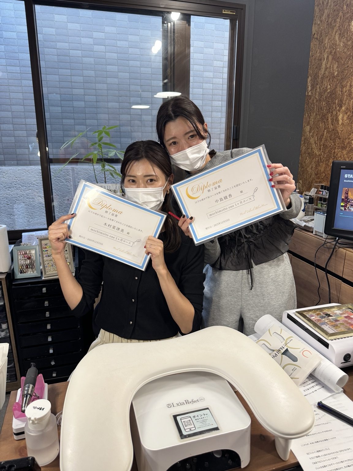 ディプロマを手にする受講生2人の記念写真